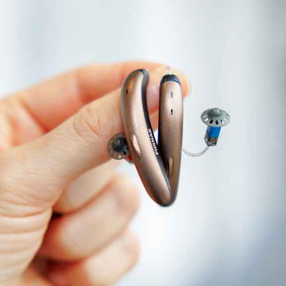 someone holding phonak slim hearing aids in sandalwood/black