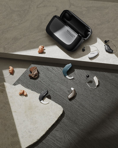 Resound hearing aid charger surrounded by Resound hearing aids.