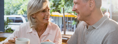 man and woman chatting in cafe wearing hearing aids