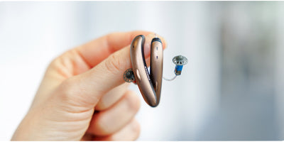 person holding bronze phonak hearing aids