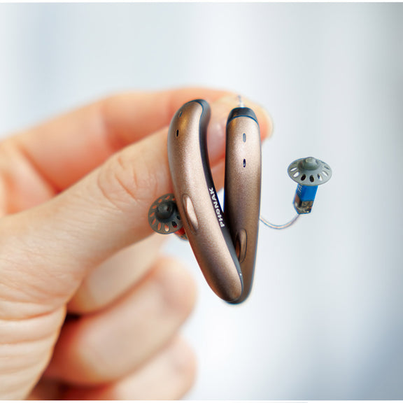 person holding bronze phonak hearing aids