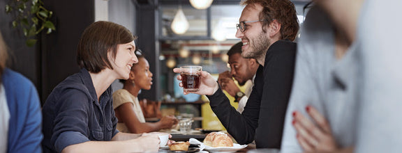 people chatting at a busy table wearing hearing aids