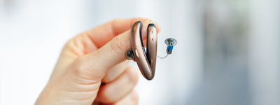 someone holding phonak slim hearing aids in sandalwood/black