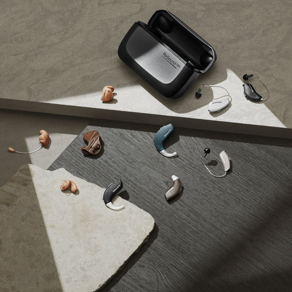 Resound hearing aid charger surrounded by Resound hearing aids.