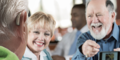elderly people communicating happily while wearing hearing aids