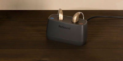 gold resound hearing aids sitting in black  charger
