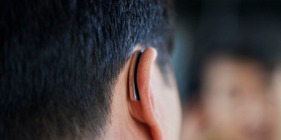 Someone wearing a Signia styletto hearing aid on their right ear.